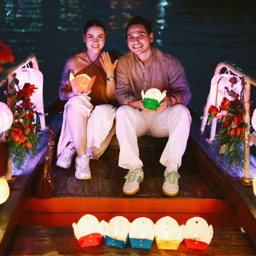 Couple holding lanterns on a boat in Hoi An at night